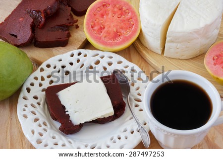 Brazilian dessert Romeo and Juliet, goiabada and Minas cheese with cup of coffee and fresh goiaba on wooden table. Selective focus