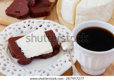 Brazilian dessert Romeo and Juliet, goiabada and Minas cheese with cup of coffee on wooden table. Selective focus