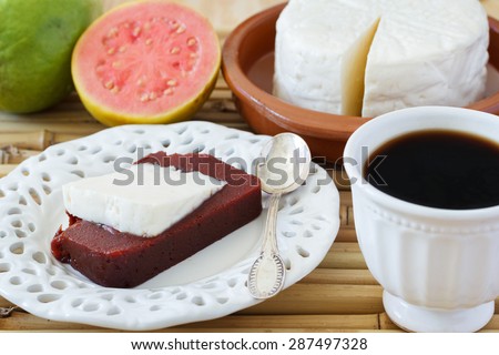Brazilian dessert Romeo and Juliet on white plate, goiabada and Minas cheese with cup of coffee and fresh goiaba on wooden table bamboo. Selective focus