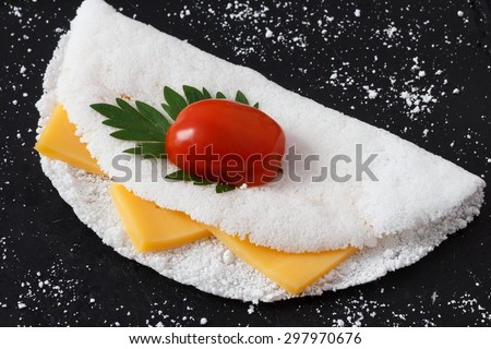 Casabe (bammy, beiju, bob, biju) - flatbread made from cassava (tapioca) with cheese, cherry tomato and parsley on pan. Selective focus