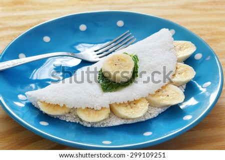 Casabe (bammy, beiju, bob, biju) - flatbread made from cassava (tapioca) with banana on blue plate. Selective focus