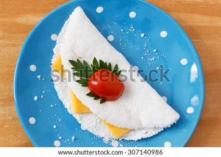 Casabe (bammy, beiju, bob, biju) - flatbread made from cassava (tapioca) with cheese, cherry tomato and parsley on blue plate. Selective focus