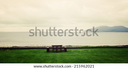 Picnic Table Benches and seascape in Waterville, County Kerry - vintage effect. Outdoor Table along the Ring of Kerry - retro photo. Panoramic coastal photo. Ireland. Wide photo for web page slider.