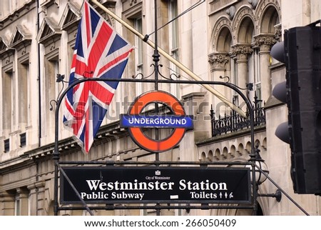 LONDON, ENGLAND -12 MARCH 2015- Editorial: Entrance sign for the London Underground (familiarly called the Tube) Westminster Station with a British flag.