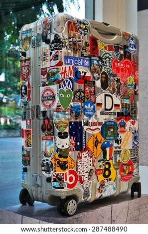 SINGAPORE -2 AUGUST 2014- A worn-out metal suitcase decorated with many travel stickers in a Rimowa store.