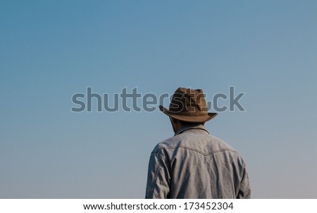 Young man stands a back looking to blue sky