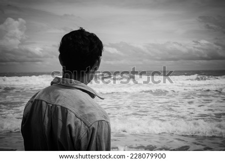 Young man standing on the beach looking to sea  ,Black and white