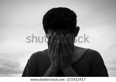 Young man crying in his hands ,Sad concept black and white photography