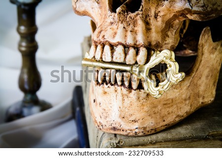 Key in the mouth  human skull on old book,Still life photography