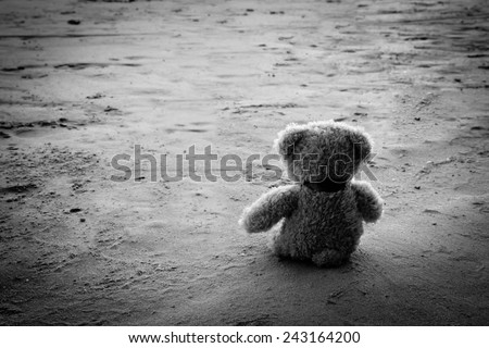 Teddy bear alone sit in beach ,sad concept black and white photography