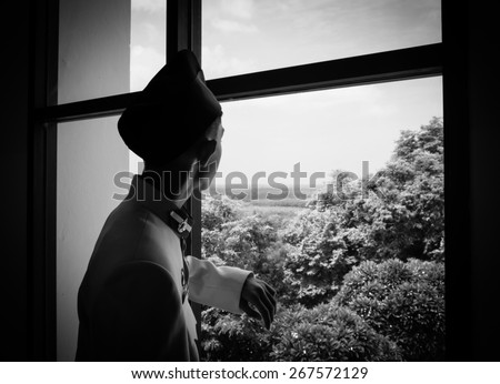 Sad teenager looking out on window, black-and-white photo