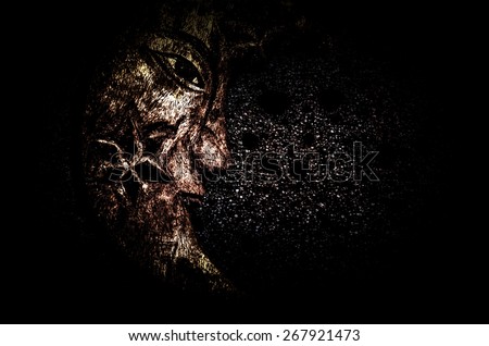 Double exposure of wood carved face with dark background