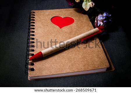 Pen on recycled  paper brow notebook with red heart ,still life