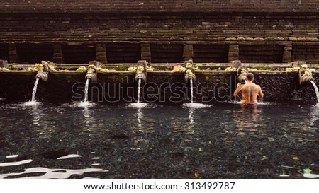 BALI, INDONESIA - 19TH JUNE 2015; People praying at holy spring water temple Puru Tirtha Empul during the religious ceremony  in Tampak Siring, Bali, Indonesia.