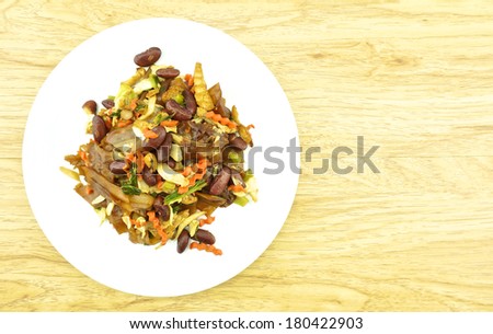 Fired thin noodles with soy sauce vegetarian in plate placed on brown wood background