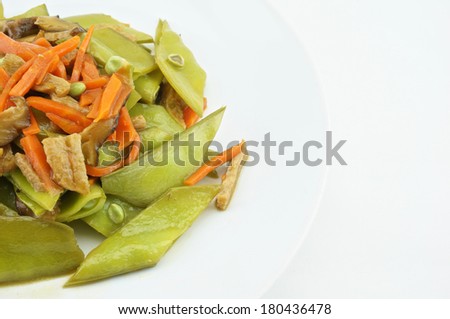 Green peas fried with carrot, mushroom and vegan protein on white dish with white background.