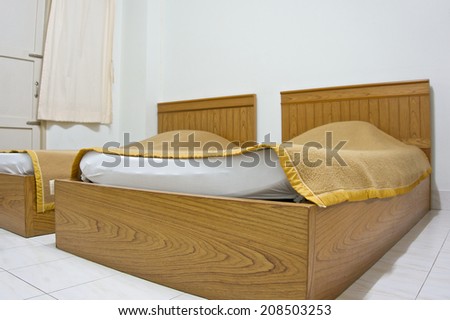 Twin brown bed and blanket on white mattress in bedroom at hotel.