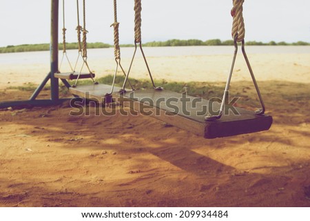 Wooden swings on beach near sea in the vintage style.