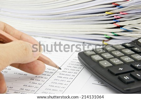 Man is auditing account with pencil and calculator on the statement finance account.