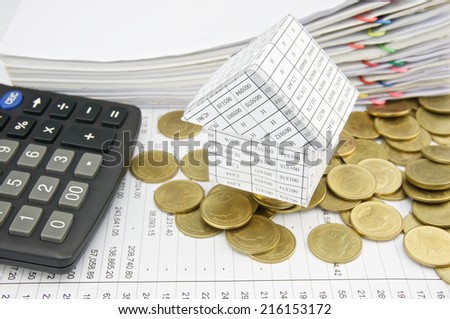 House on pile gold coins and calculator place on finance account with pile of paperwork as background.