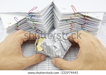 Man open gift box of gold coin place on finance account with pile of paperwork as background.