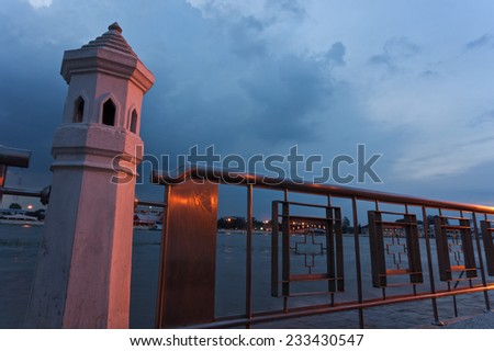 Concrete and iron fence beside river with sky at night.