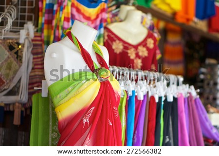 Red yellow green dress on white mannequin in clothing market.