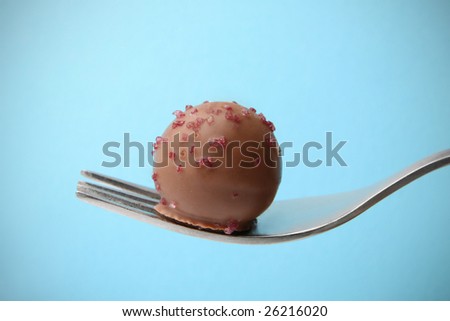 Sweet bite. Chocolate praline on the fork ready to eat.