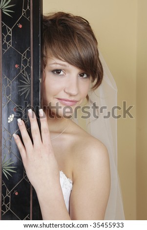 Bride getting ready peeking from behind the screen