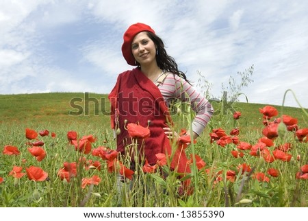 Red explosion, cute girl with red hat and red scarf stands among red poppies