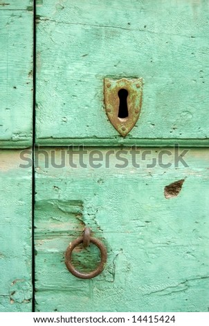 Rusty key slot and knocker on turquoise antique door