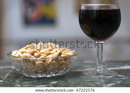 Glass of red wine and peanuts at the bar, selective focus