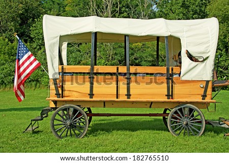 Horse drawn covered wagon with an American flag.