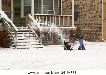 CHICAGO, ILLINOIS,, USA- Nov 21: A man is cleaning snow off sidewalk with a snow blower on Nov 21, 2015 in Chicago, Illinois, USA