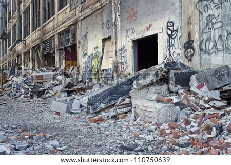 Illegally painted graffiti in an abandoned building in Detroit, Michigan. The Windows are broken out and piles of bricks and old tires are scattered about.