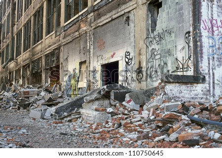 Illegally painted graffiti in an abandoned building in Detroit, Michigan. The Windows are broken out and piles of bricks and old tires are scattered about.