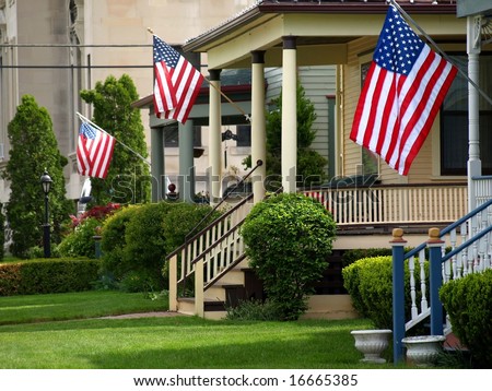 American flags flying proudly on front porches of a small town during a holiday