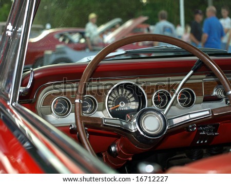 View from classic red convertible through windshield at a car show