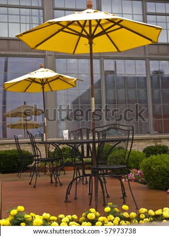 Sidewalk cafe with metal tables and chairs that have bright yellow umbrellas on them