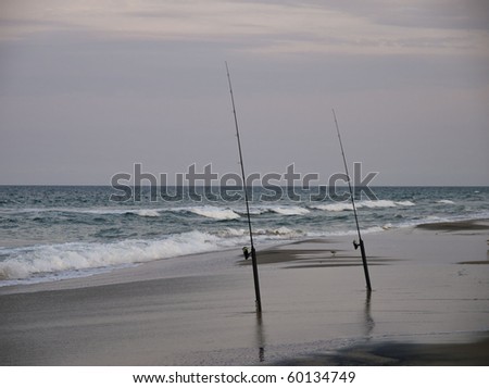 Surf fishing off of North Carolina\'s Outer Banks in the Atlantic Ocean. The sun is setting and there is a pinkish glow to the sky.