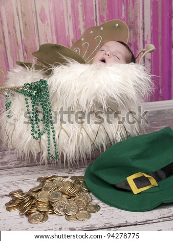 Beautiful one week old newborn sleeping with wings beautiful Irish Fairy Princess. The leprechaun has left behind his gold coins and hat.