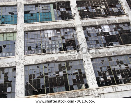 Exterior of an abandoned automobile manufacturing plant in Detroit Michigan. Most of the windows are broken.