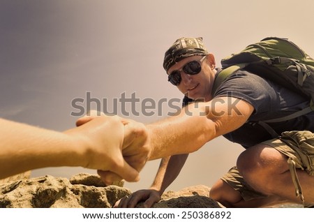 Tourist man helps someone to climb the mountain