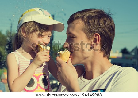 Little girl eating ice cream on the street in the summer in the company of his father