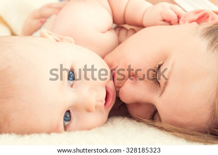 Portrait of beautiful young mother with a baby. Mother kisses the child.