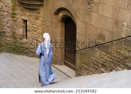 LE MONT SAINT-MICHEL, FRANCE - JULY 26, 2014: A sister is walking down the stairs in the Mont Saint-Michel which is one of the World Heritage Sites in France.