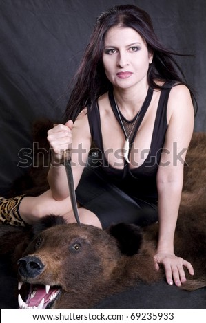 sexy woman with a dagger sits on the bear skin