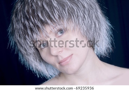 Portrait of the nice young woman in a cap from fur of a polar fox