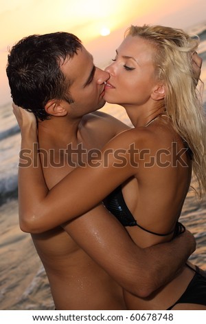 stock photo Romantic couple kissing on a beach at sunset