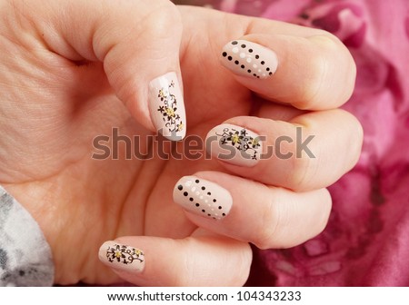 Female hand with nude and black  manicure close up. With dots and  flowers. On the red background.